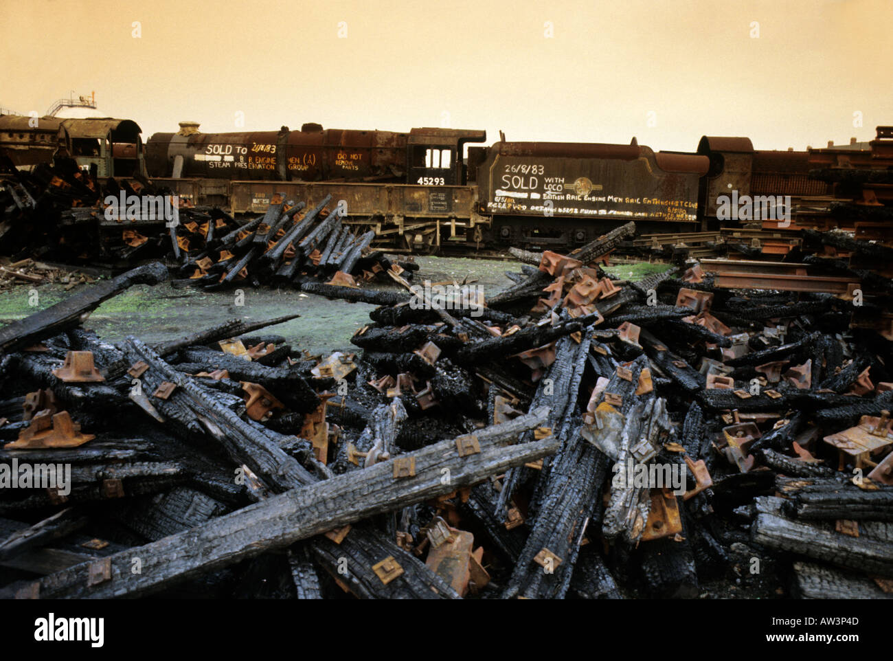 Rusting steam train and burned sleepers in scrap yard Barry Wales UK Stock Photo