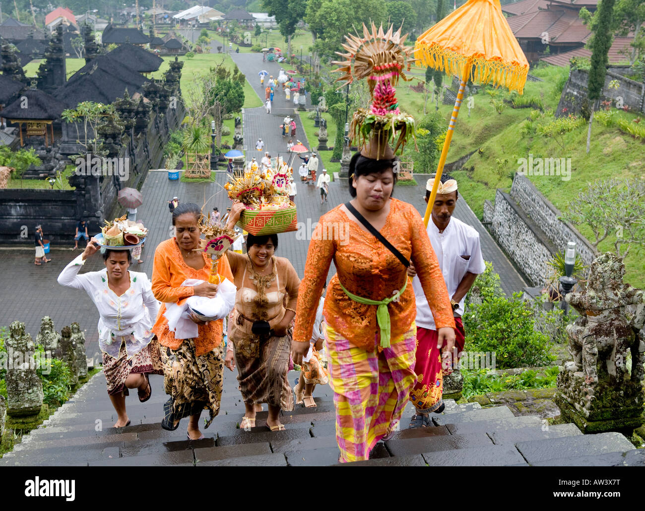 Balinese Funeral Procession Carrying Umbrellas and Votive offerings Climbing Steps Up To The Pura Besakih Temple Bali Indonesia Stock Photo