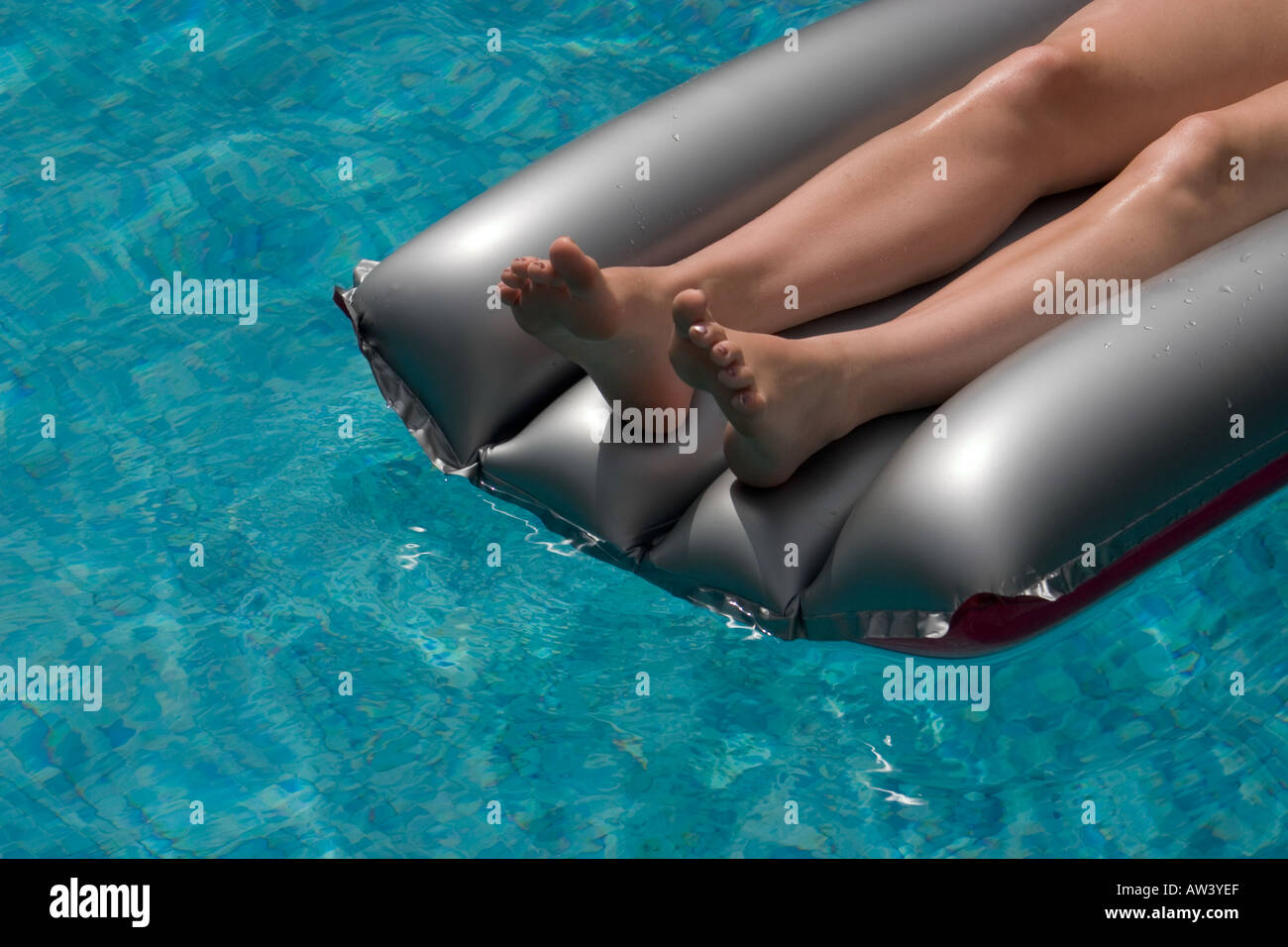 Young womans legs on inflateable airbed floating on water Stock Photo