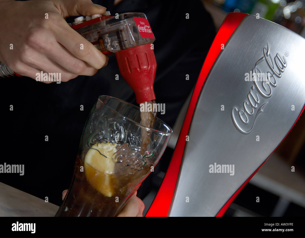 barperson topping up a glass with cola from a dispensing gun Stock Photo