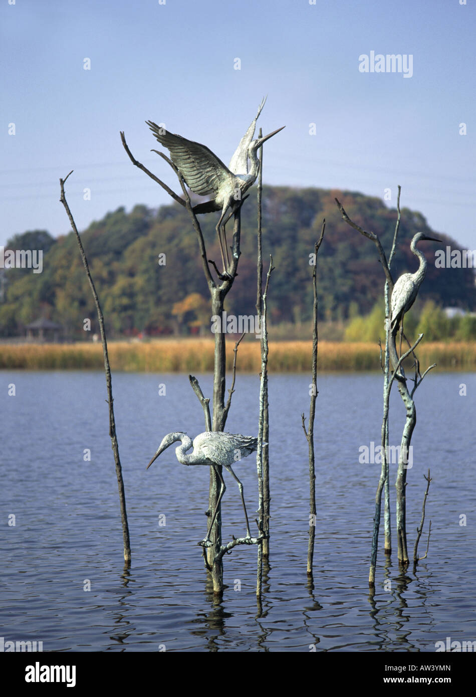 Sculpture of cranes on bare branches  In water  Two perched  One wings outstretched Stock Photo