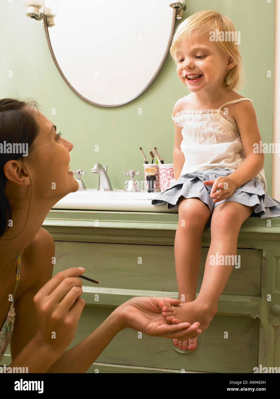 Mother and daughter applying makeup. Stock Photo