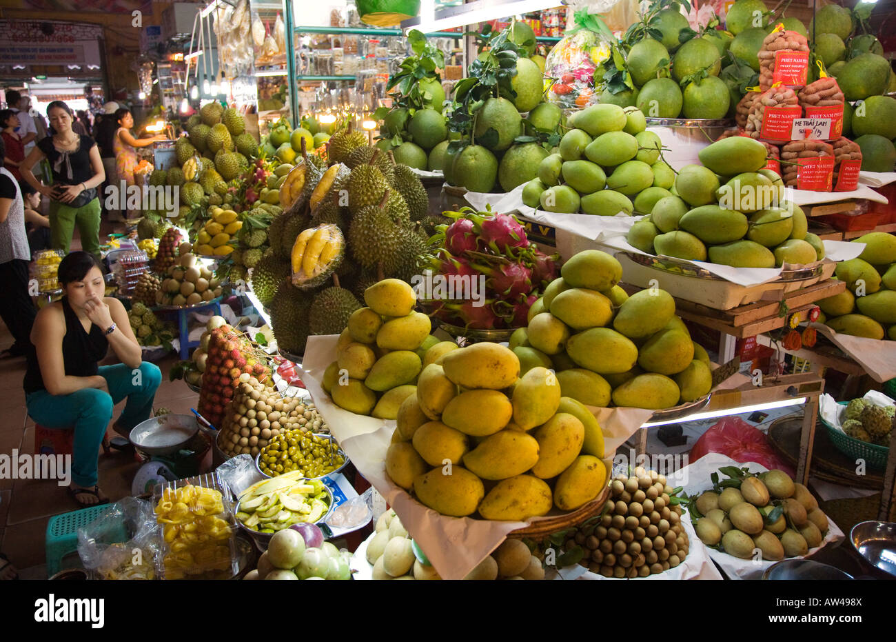 Saigon fruit seller watches over DURIAN fruit MANGOES and other edibles in the BEN THANH MARKET HO CHI MINH CITY VIETNAM Stock Photo