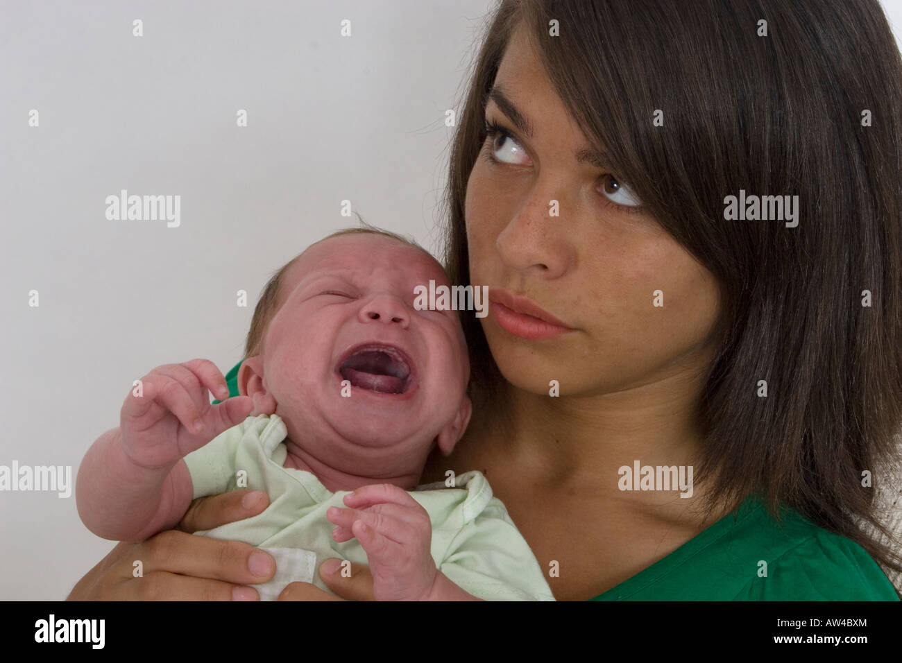 distraught young mother or childminder holding crying baby Stock Photo