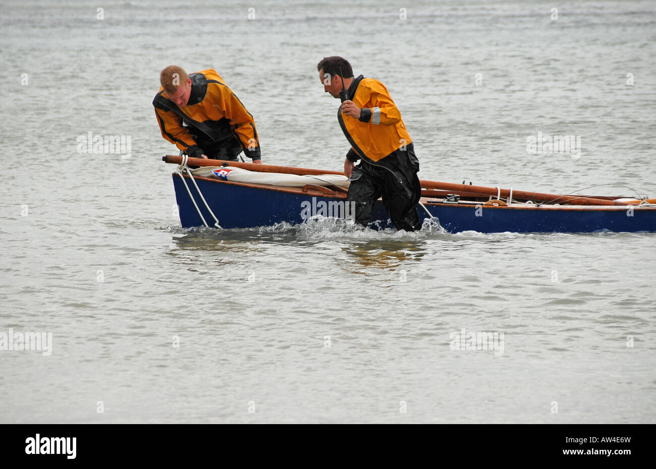 Two RNLI lifeboat crew pulling in capsized sailing dinghy on Sheringham