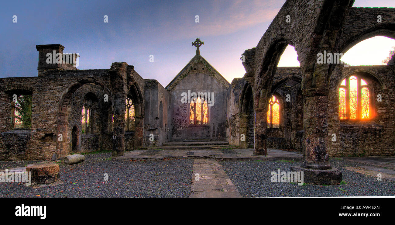 Interior of a burnt out church attacked by arsonists and left as a ruin with a blazing sunrise through the glassless windows Stock Photo