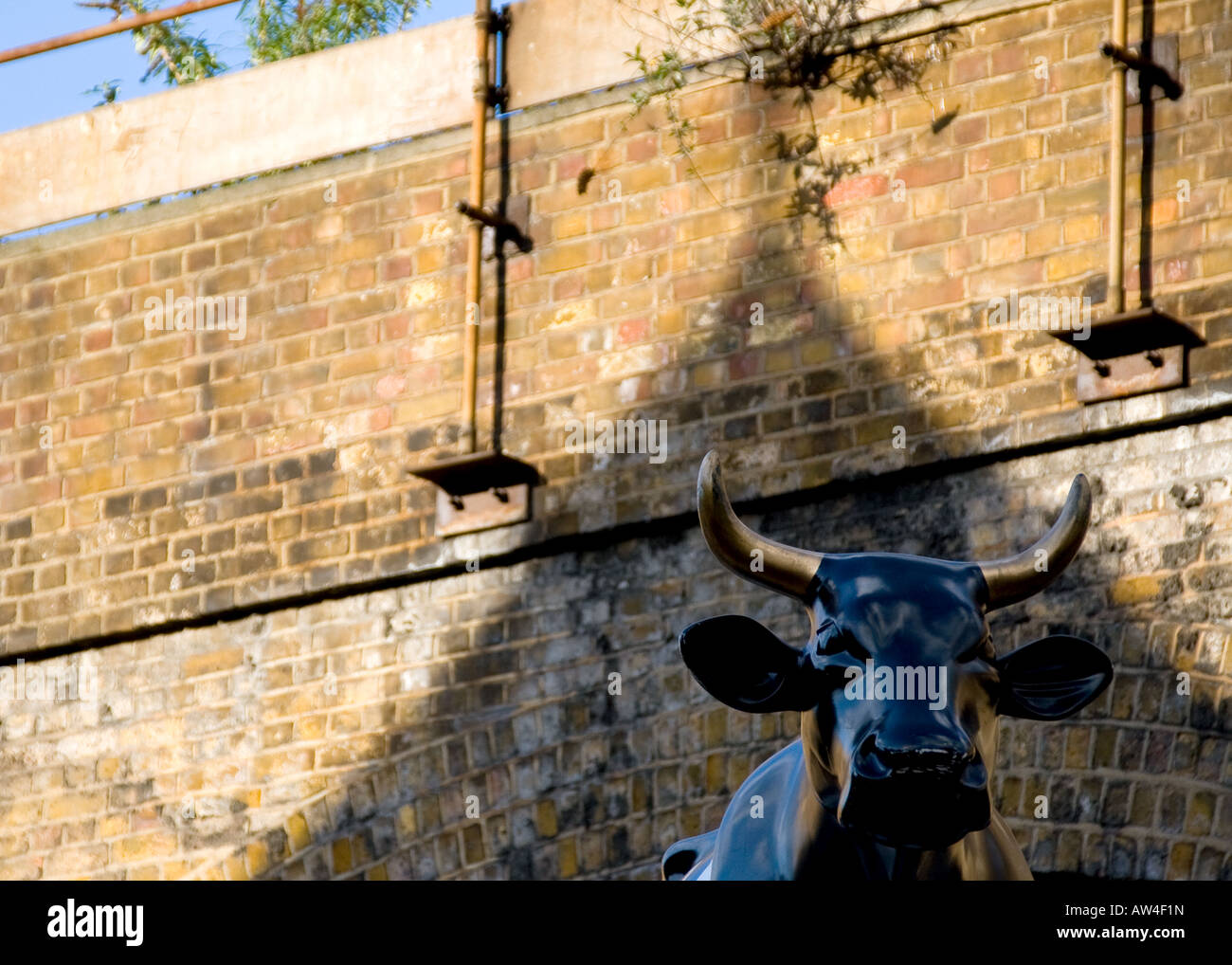 black and gold statue of bull underneath london railway bridge Stock Photo