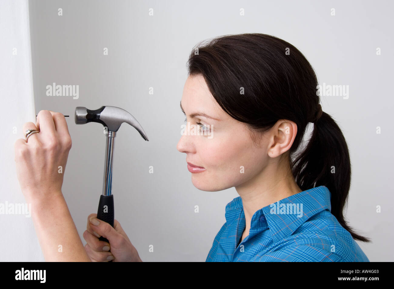 woman hammering a nail into the wall Stock Photo