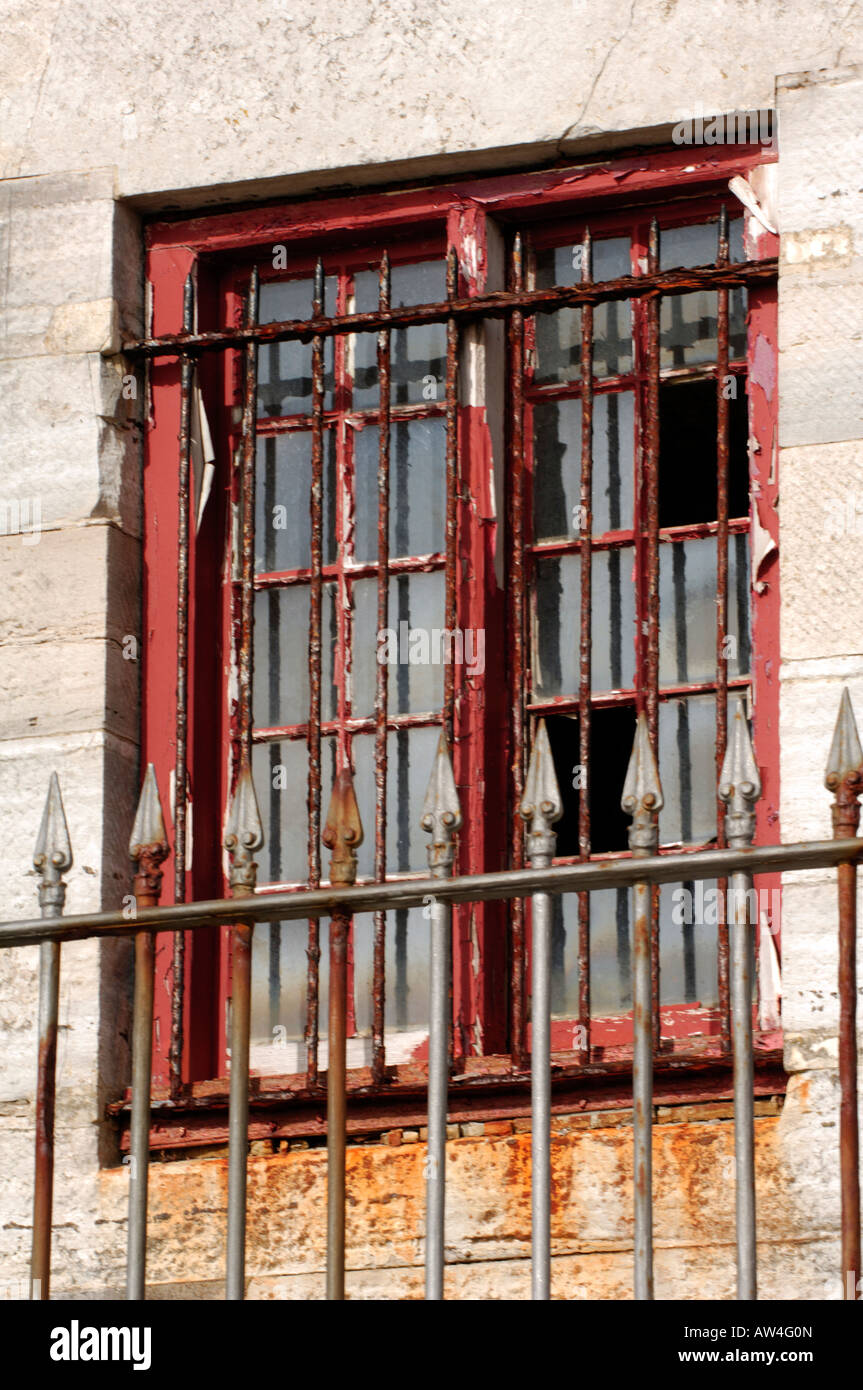 an old broken window with railings and bars protecting it ina derilect