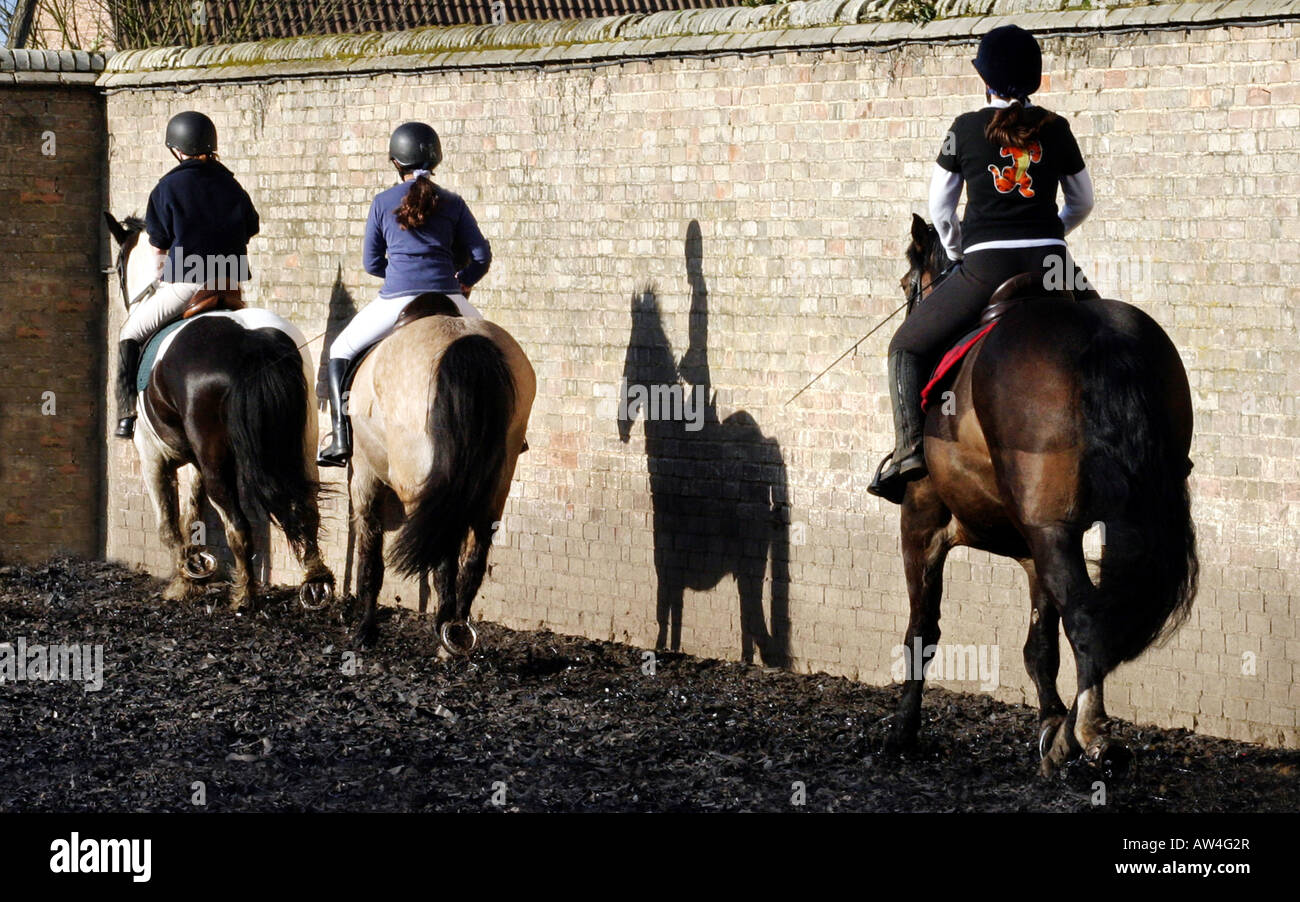 A line of girls in riding school with a shadow rider between them, Cambridgeshire, UK Stock Photo
