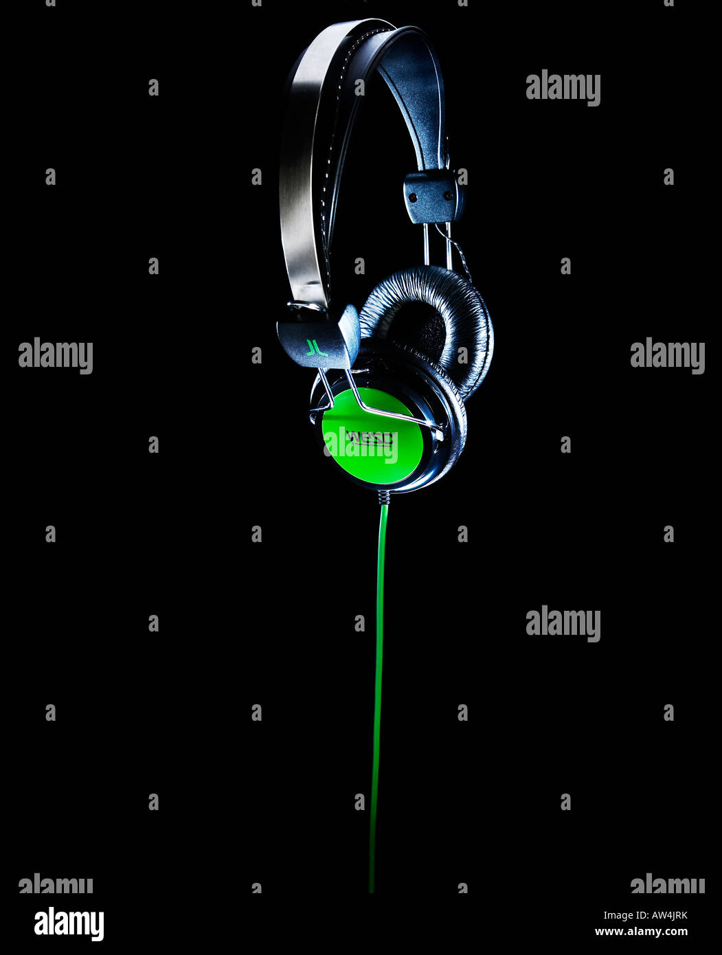 headphones with a green cable suspended in air on a black background Stock Photo