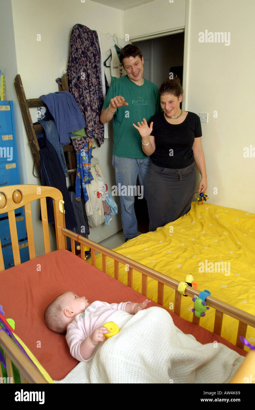 Five month old baby in crib for night time with parent waving goodnight