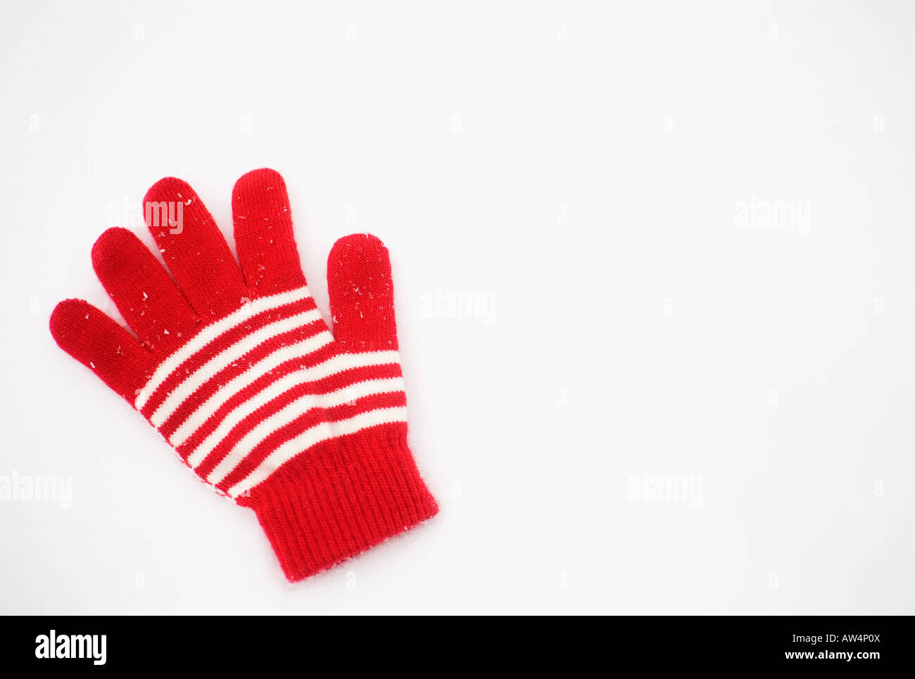 One red and white glove laying in the snow Stock Photo