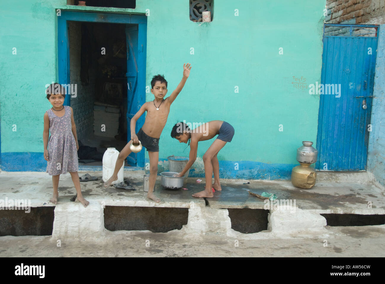 Children waving and bathing in front of their home in rural India Stock Photo