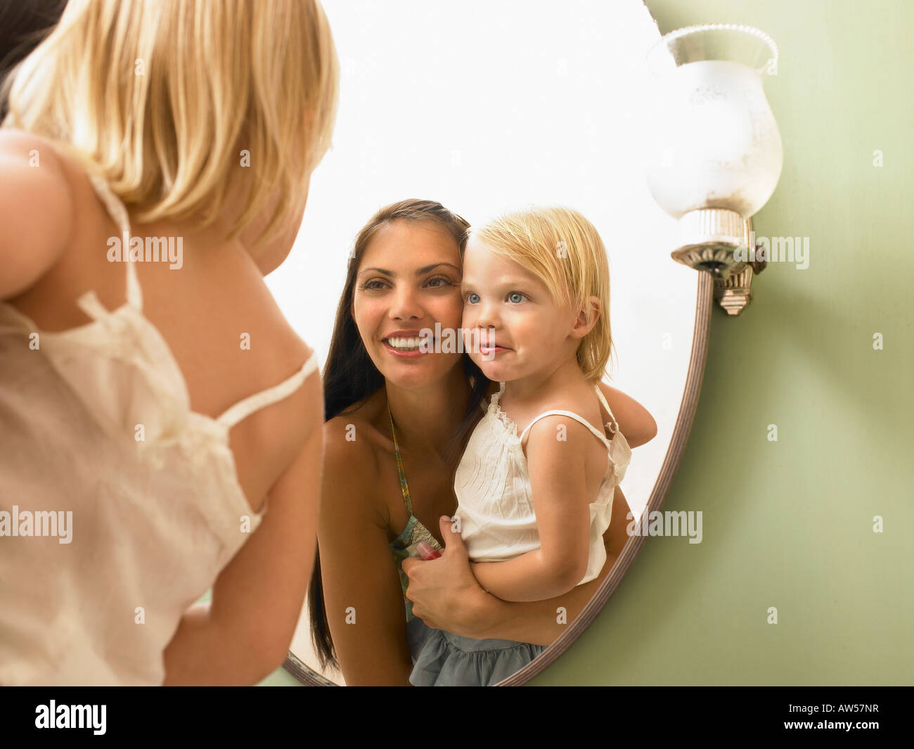 Mother and daughter looking at mirror. Stock Photo