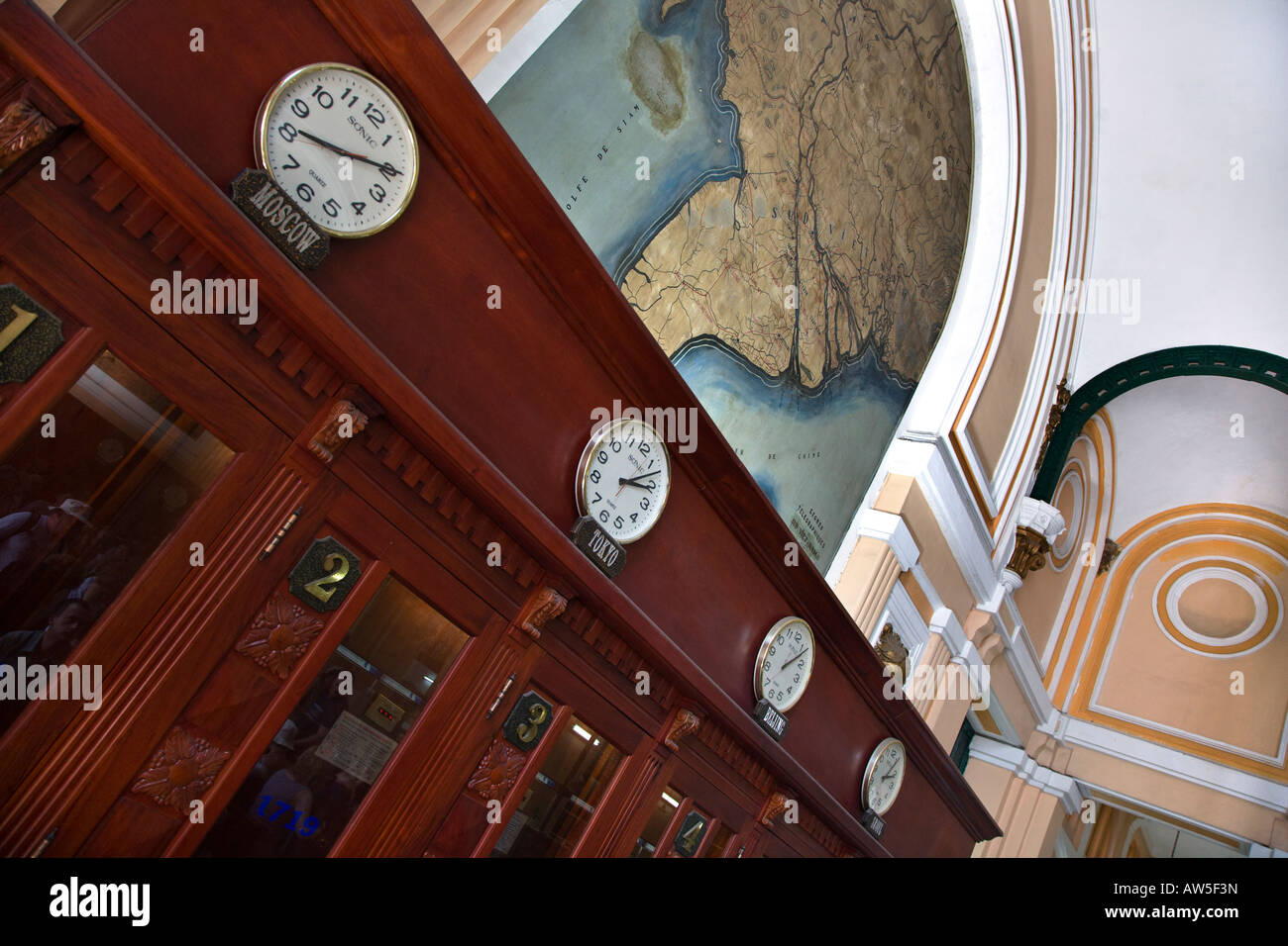 Clocks showing world time above the telephone booths inside the MAIN POST OFFICE in HO CHI MINH CITY SAIGON VIETNAM Stock Photo