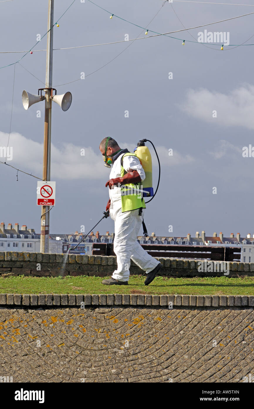 Adult male wearing a white chemical suit and face mask spraying