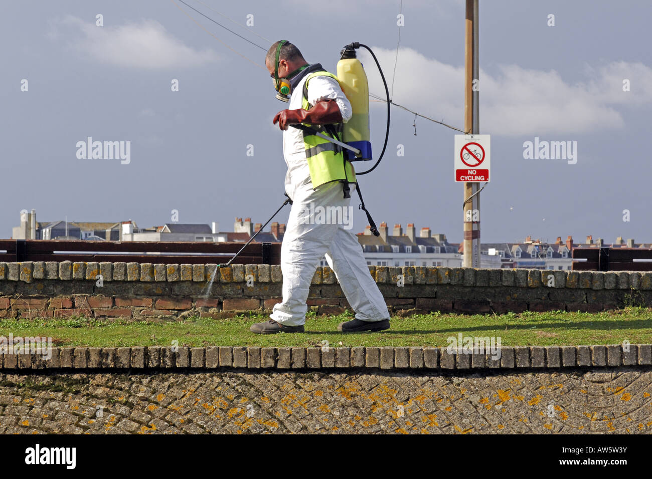 Adult male wearing a white chemical suit and face mask spraying