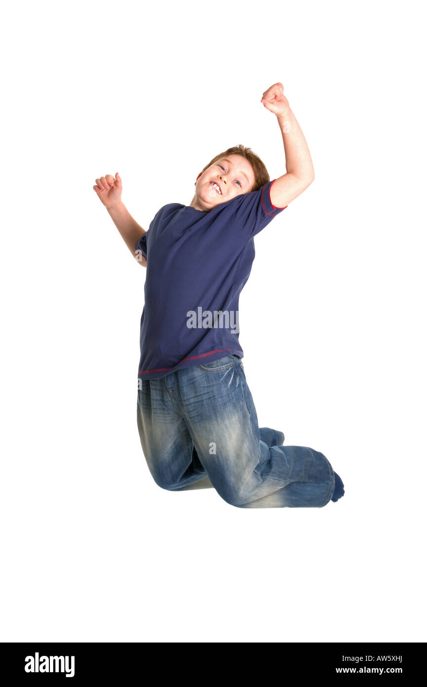 A happy young boy leaping in the air against a white background Very slight motion blur Stock Photo