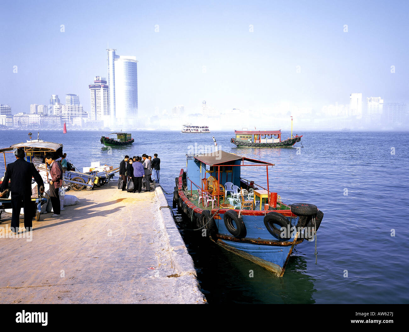 Boats at wharf on Gulangyu island, with Xiamen city in distance. Stock Photo