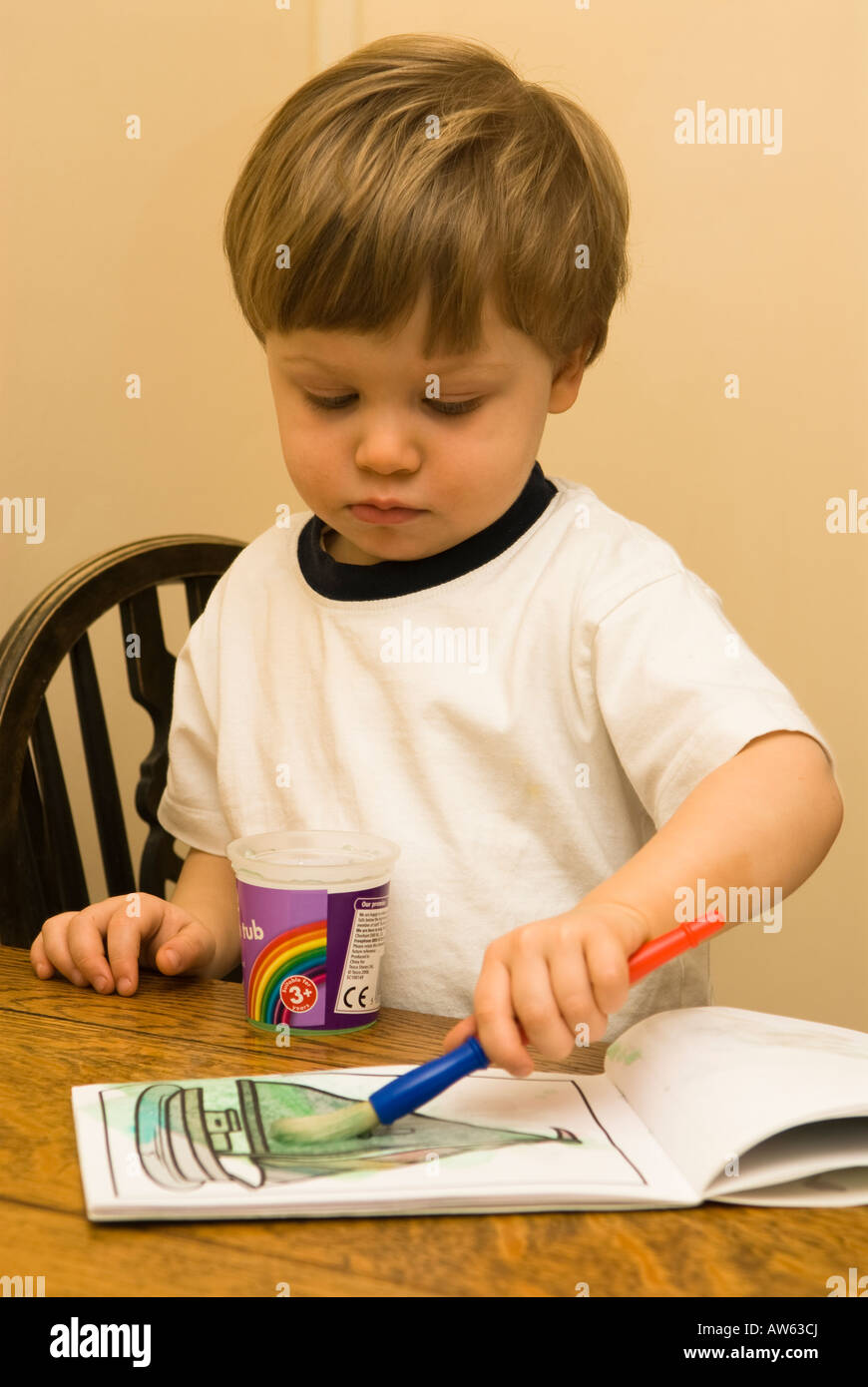 two year old boy water painting a picture at the table Stock Photo