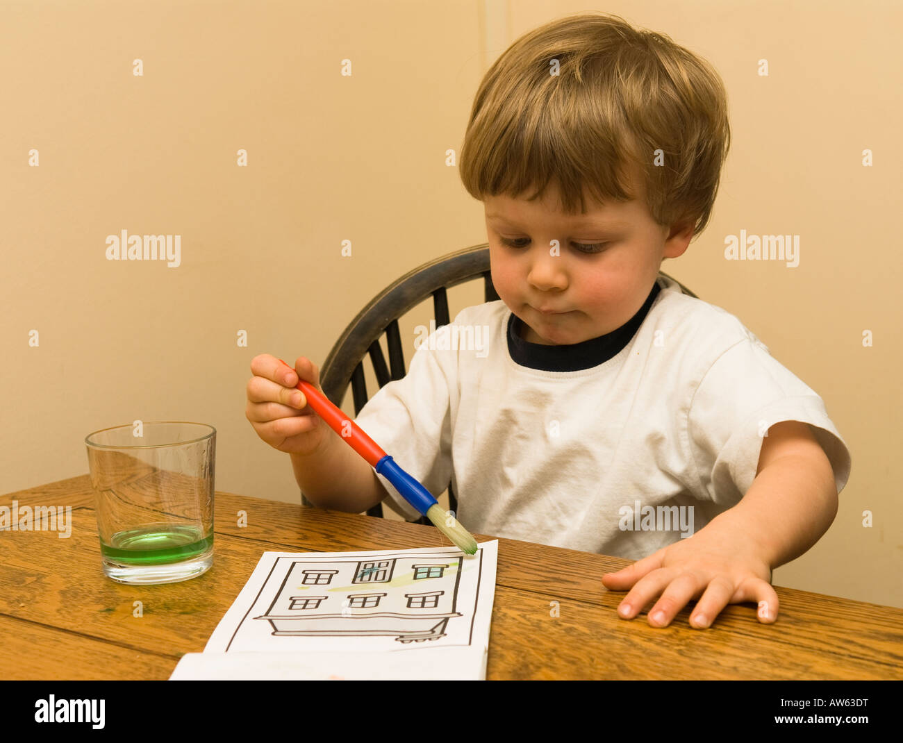 two year old boy water painting a picture at the table Stock Photo