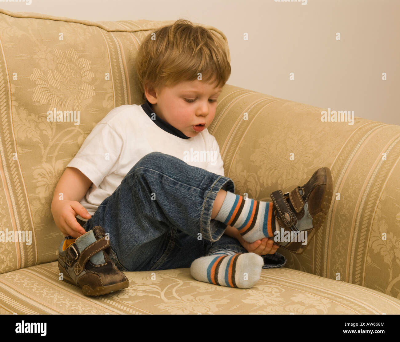 two year old boy trying to put his shoes on Stock Photo Alamy