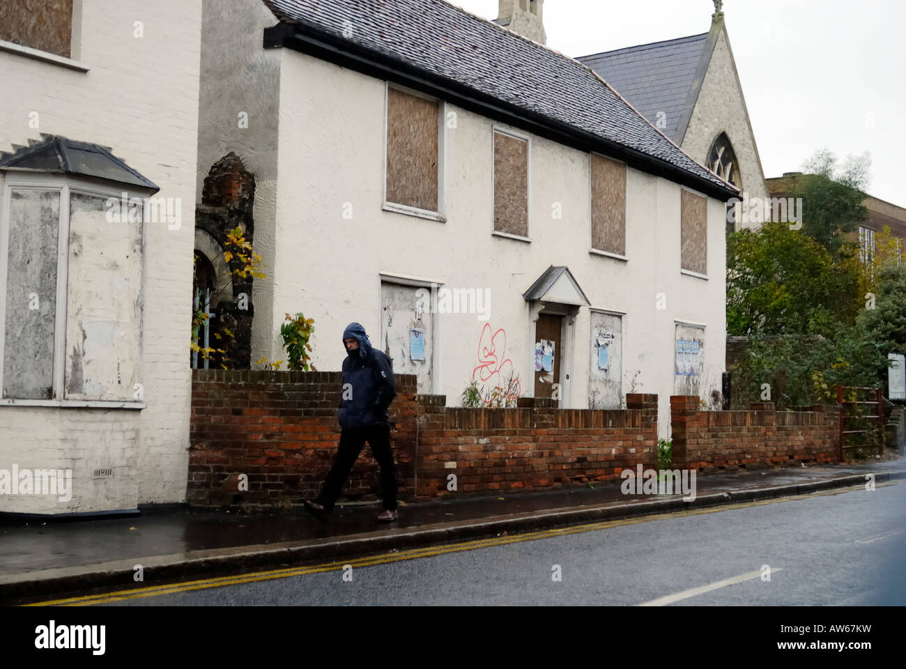 Man walking through rain past derelict buildings in Bishops Stortford Hertfordshire Stock Photo