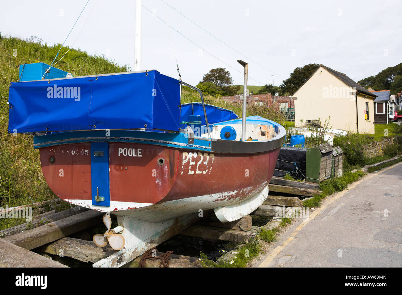 Fishing boat beside the road at Lulworth Cove, Dorset Stock Photo