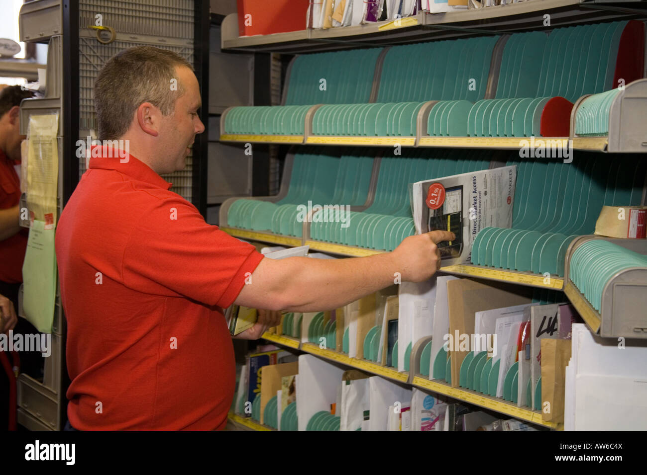 Postman post man working at his sorting office station. mail sort cases. Red tee shirt. GPO. Horizontal Narberth Post Office Stock Photo