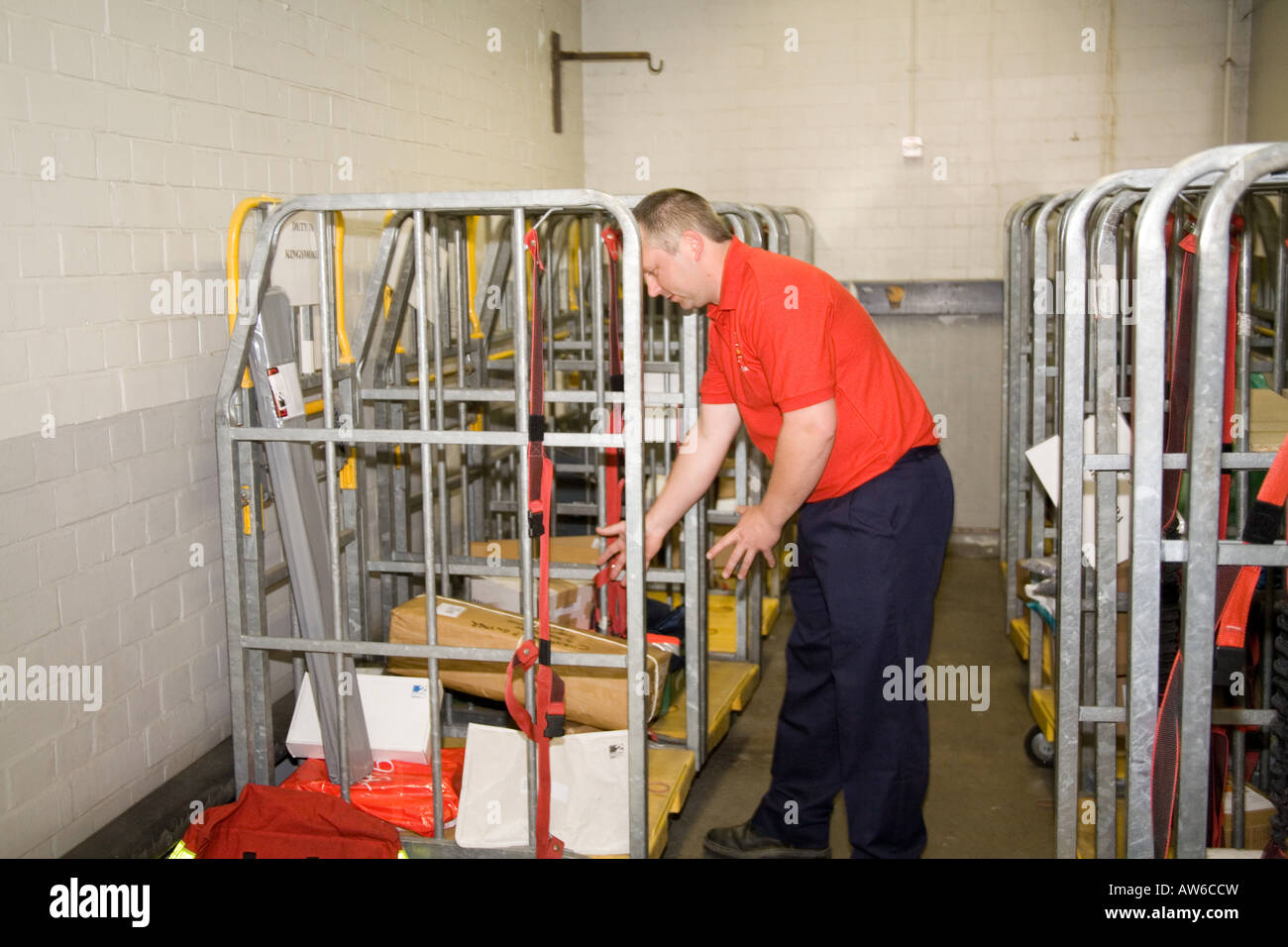Postman post man working at his sorting office station. mail sort cases. Red tee shirt. GPO. Horizontal Narberth Post Office Stock Photo