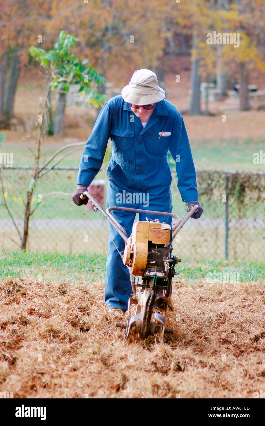 Senior men working with rototillers in public garden in USA for growing food for the homeless