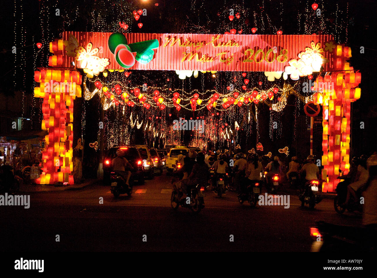 Cars and motorcycles passing through an archway of lights and decorations during the Vietnamese New Year 'Tet' celebrations 2008 Stock Photo