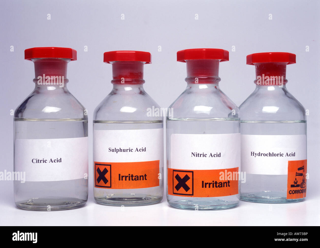 Bottles of laboratory acids with hazard labels Stock Photo