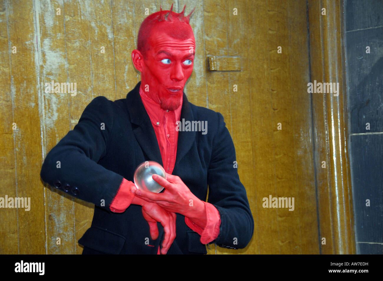 Crystal Ball street artist performing crystal ball / sphere manipulation act dressed as devil at Edinburgh Fringe Festival Stock Photo