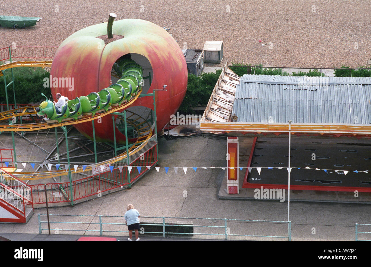 man rides on the now defunct big apple ride at brightons peter pan play ground while being watched by a woman Stock Photo