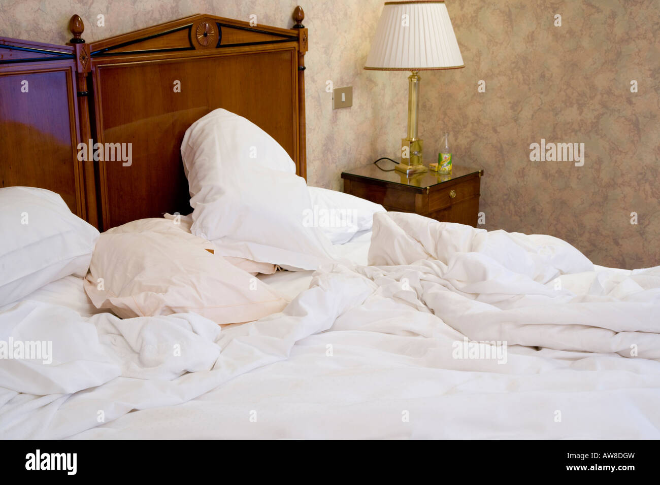 Unmade bed hotel bedroom sheets ruffled mess messy pillow untidy Stock Photo