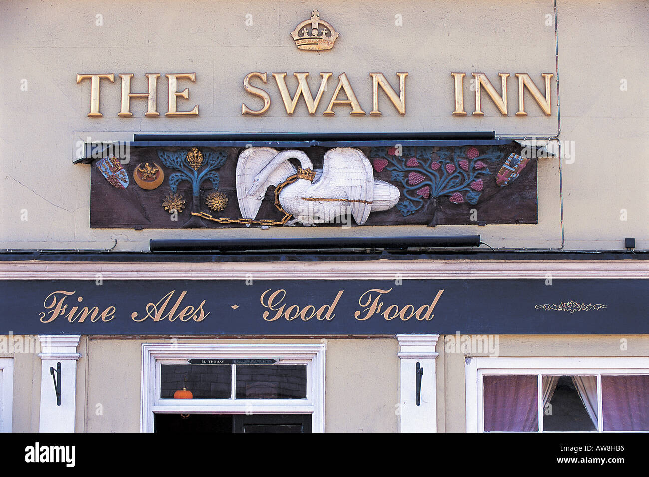 The Swan Inn at Clare Suffolk England showing the carved wooden sign of mute swan Cygnus olor Stock Photo