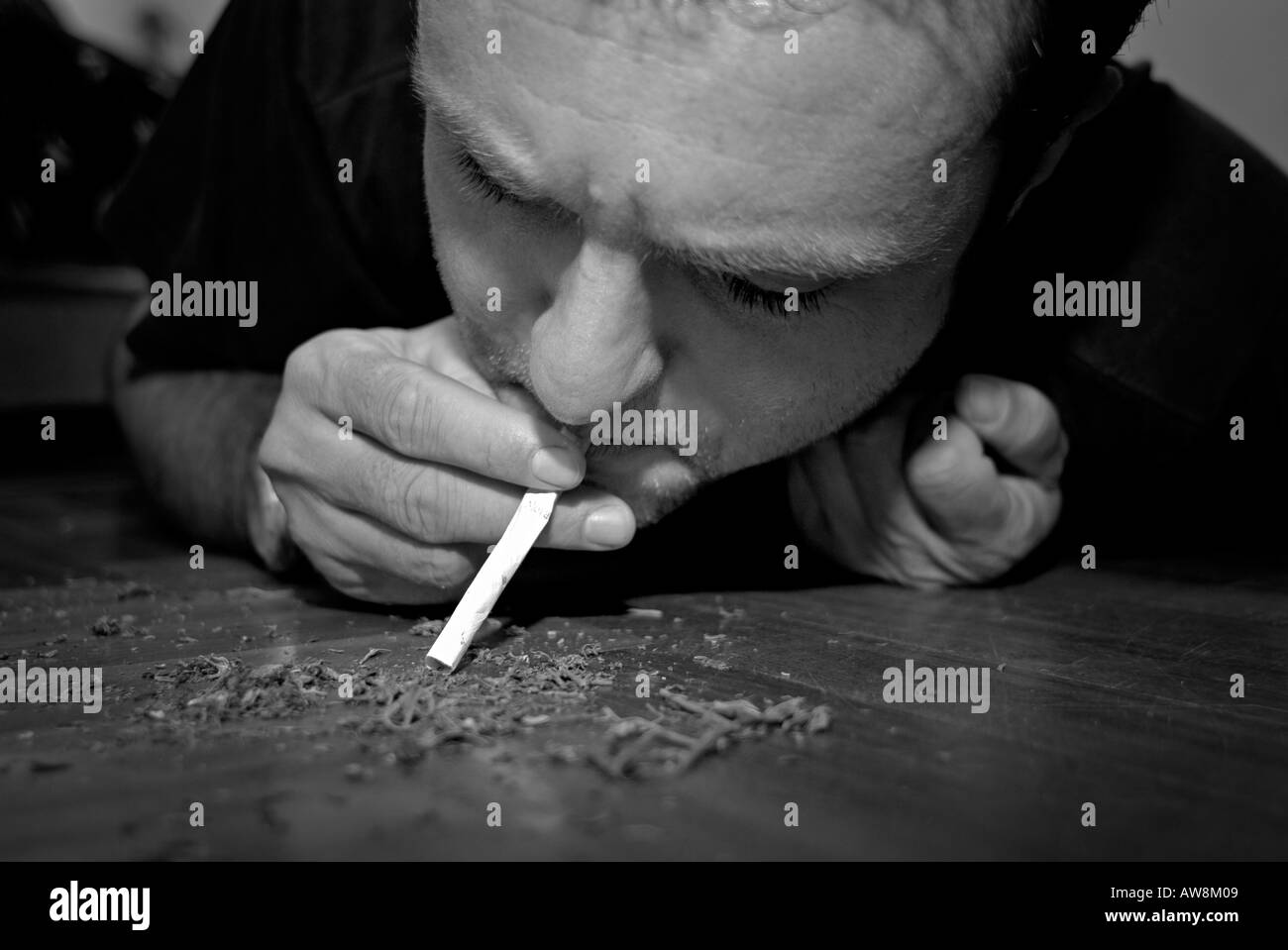 Man sucking marijuana into a normal cigarette with the tobacco and filter removed to make an Italian style joint Stock Photo