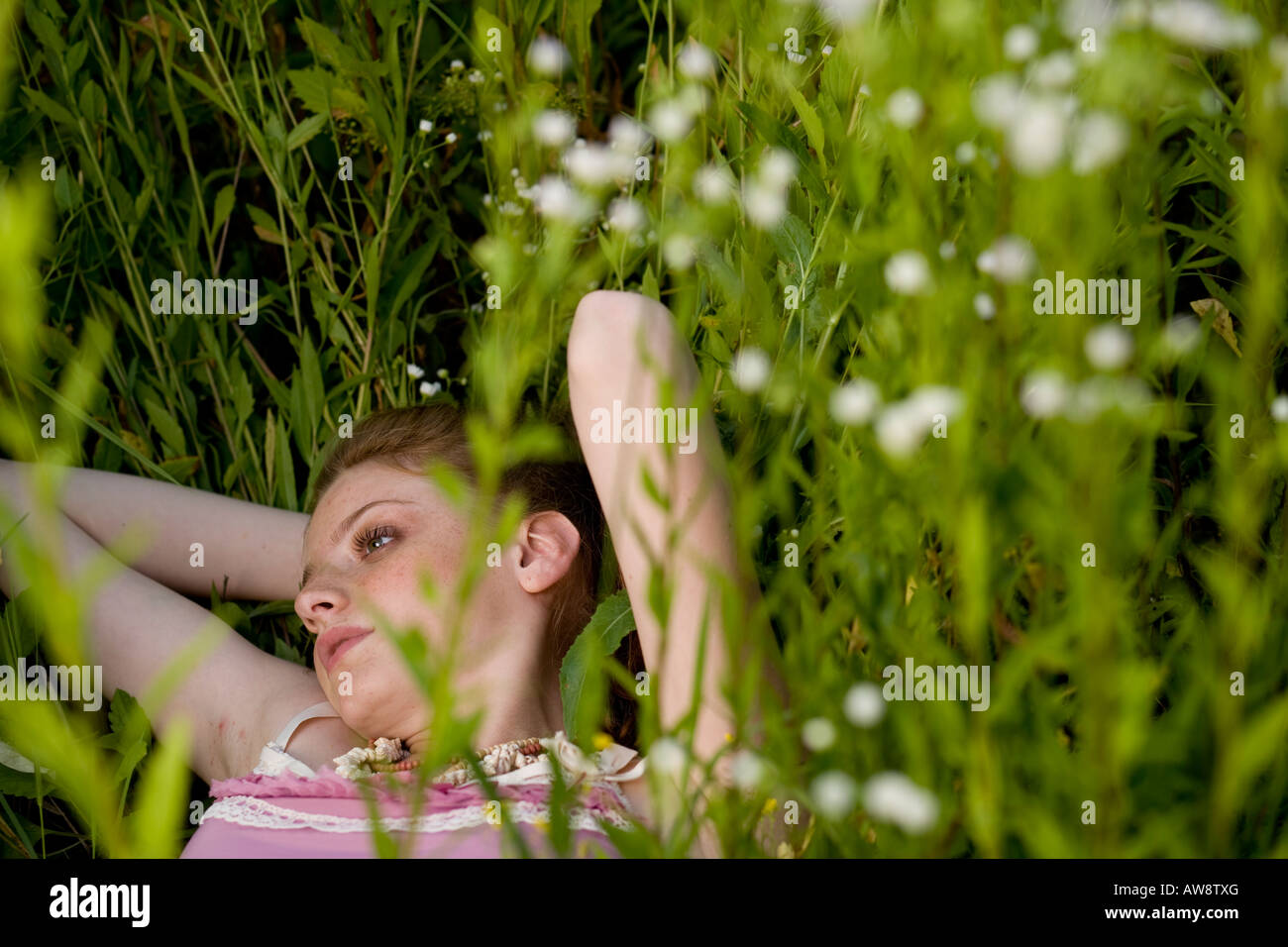 Beautiful young girl lying down on a green field Stock Photo - Alamy