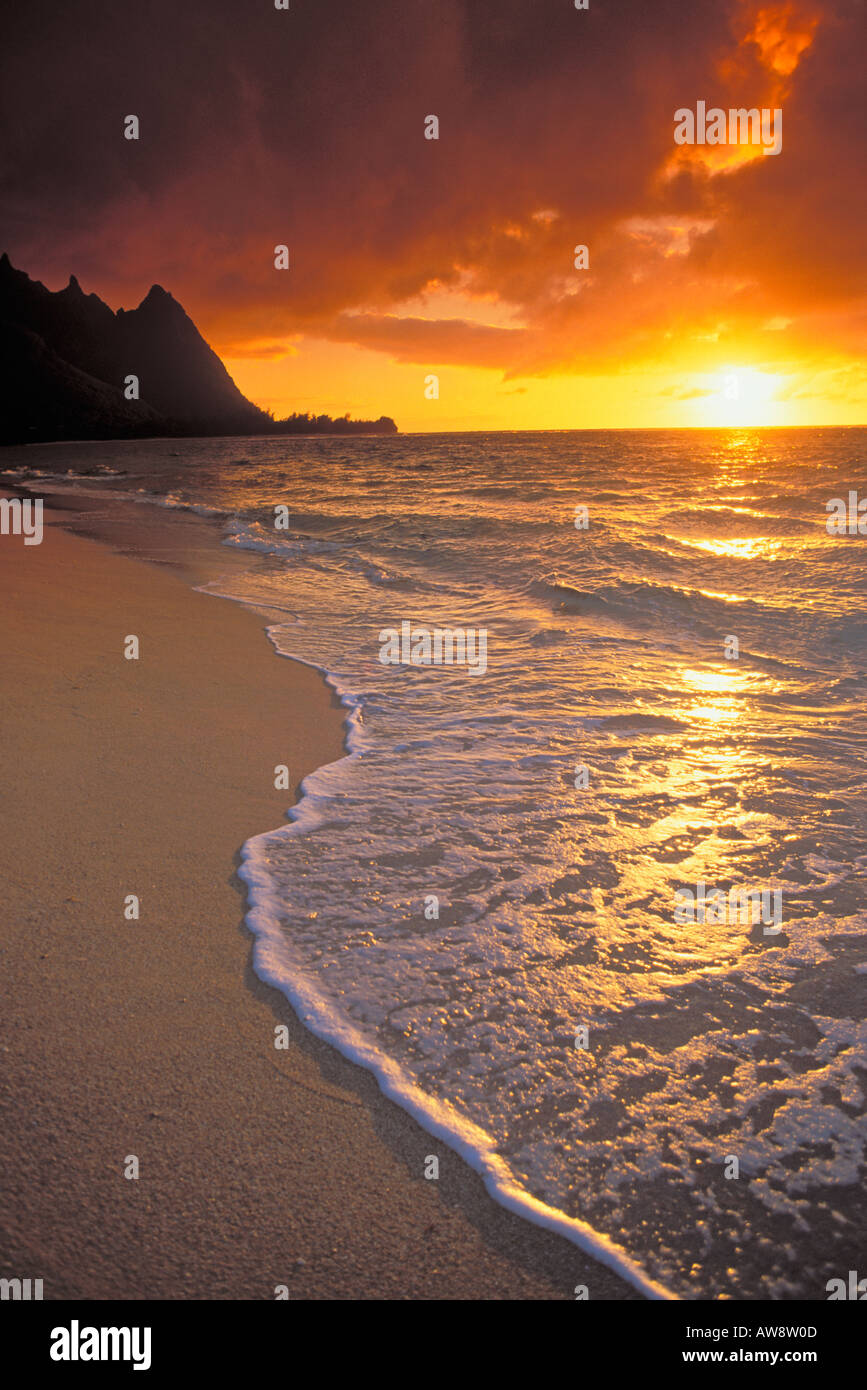 Sunset over surf sand and peaks from Tunnels Beach Haena Island of