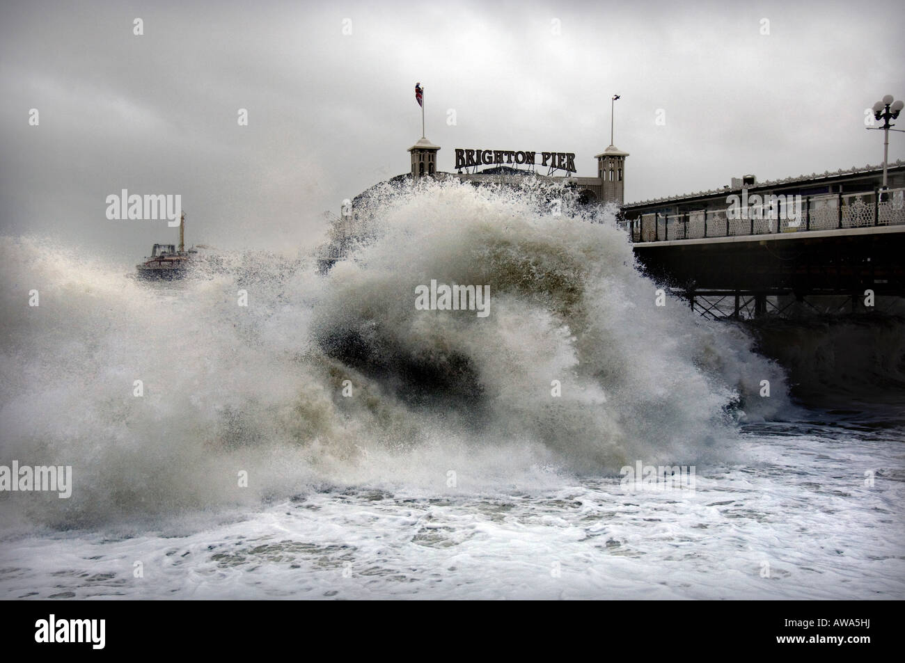 A giant wave batters the shoreline by Brighton pier as 80mph winds hit Great Britain Stock Photo