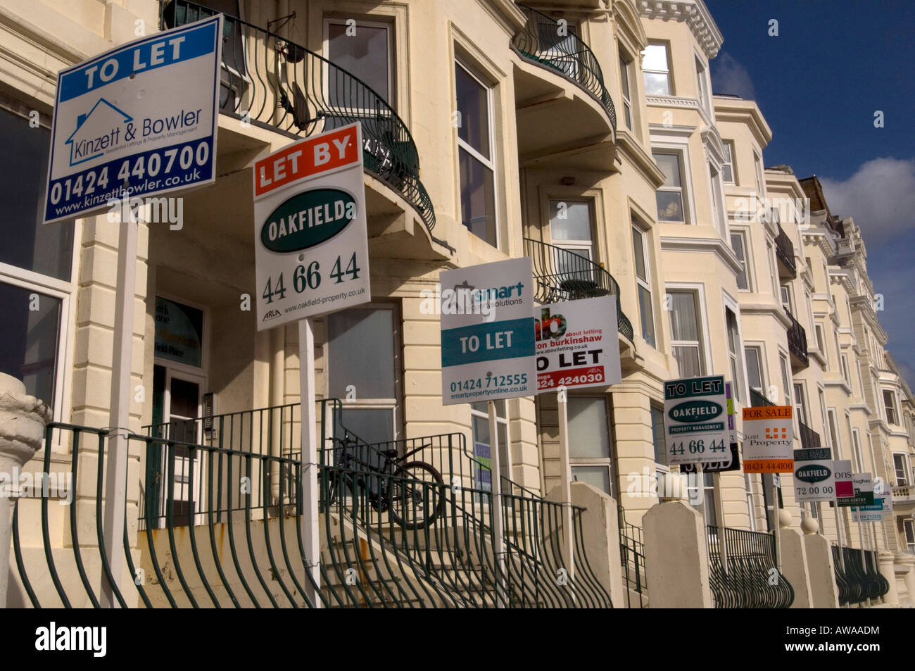 A row of Estate agents For Sale Sold Sale Agreed To Let and Let boards festoon a terrace of sea view houses on Hastings seafront Stock Photo