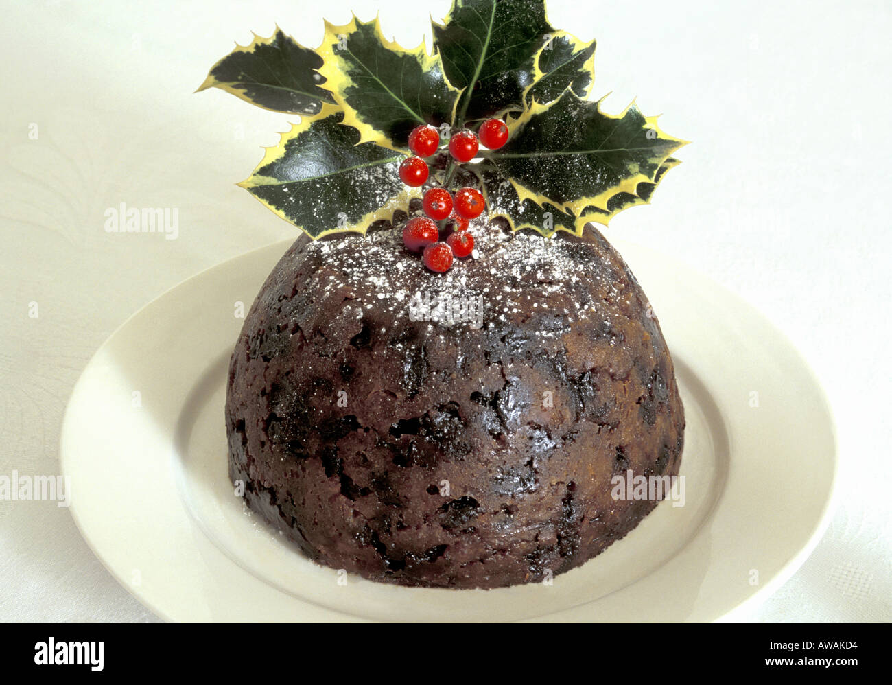 Christmas Pudding on White Plate with Variegated  Holly Stock Photo