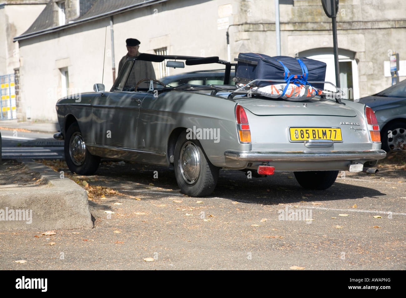 Elderly Frenchman admires old Peugeot convertible car Stock Photo
