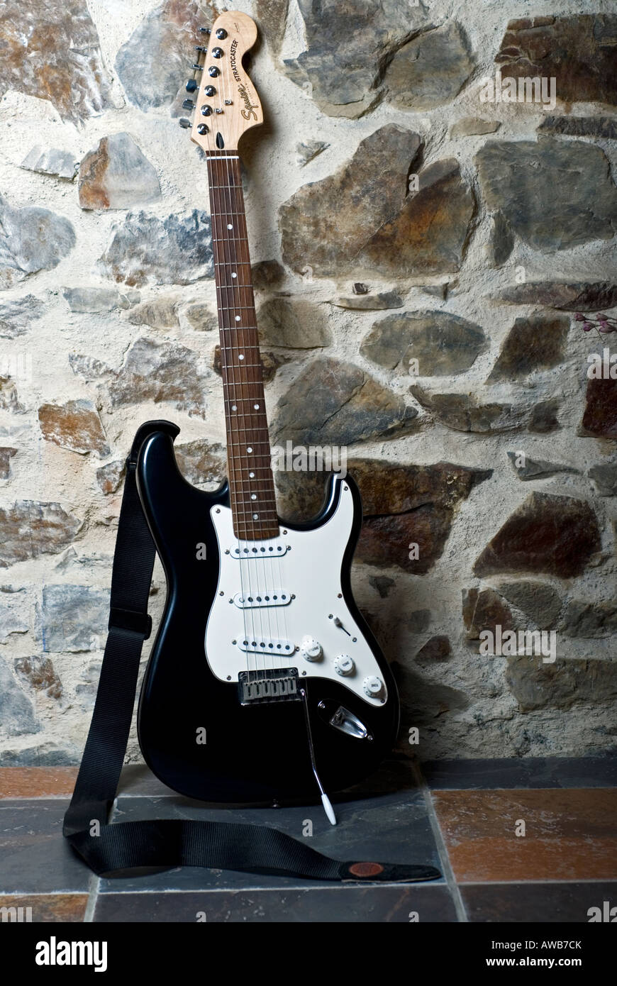 Image of a black and white electric guitar leaning against a wall Stock Photo