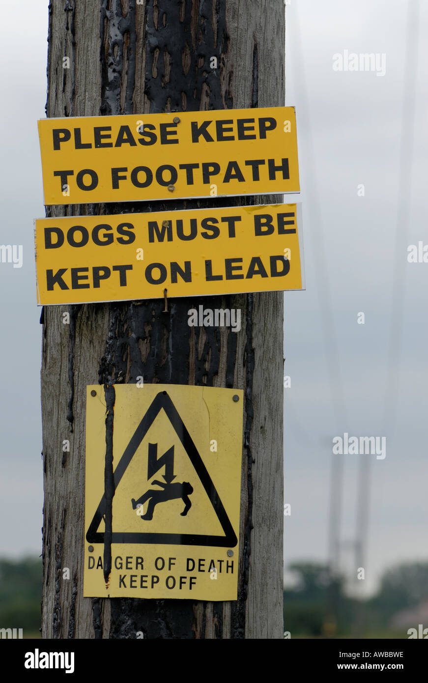 Signs on an electricity post saying Please keep to the footpath Dogs must be kept on a lead and Danger of Death Keep Off Stock Photo