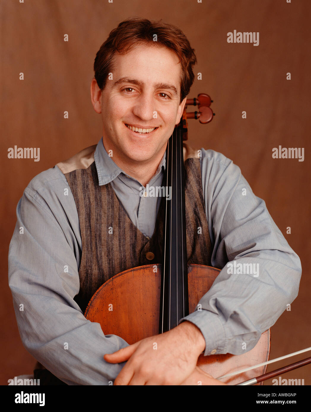 A man in his mid thirties holding a cello. Stock Photo