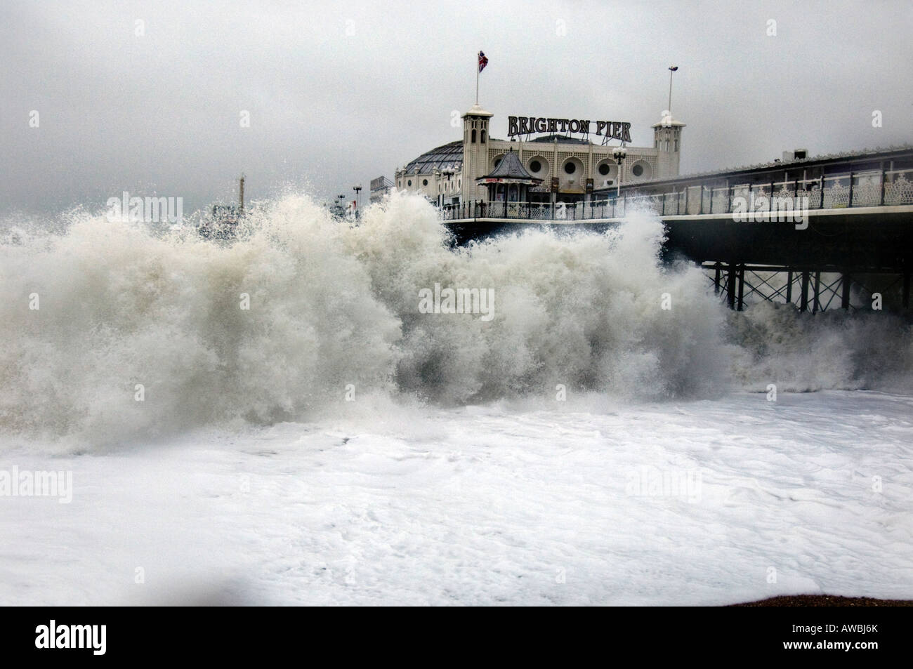 A giant wave batters the shoreline by Brighton pier as 80mph winds hit Great Britain Stock Photo