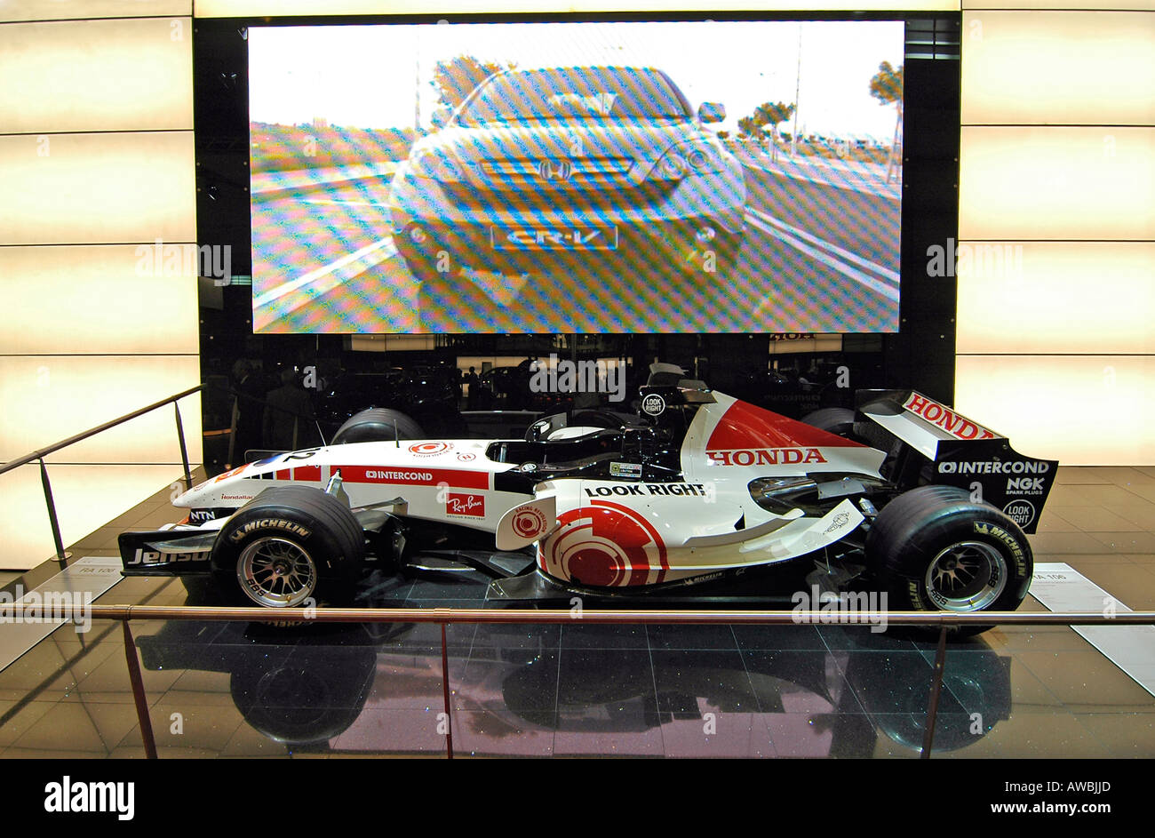 A Formula One exhibited at the Paris International Auto Show, with an advertising movie appearing on the giant screen  behind. Stock Photo